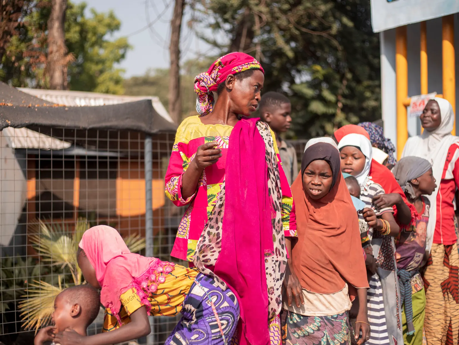 Women and children queueing along a fence for food distribution during the Joy to the Street campaign in Kumasi