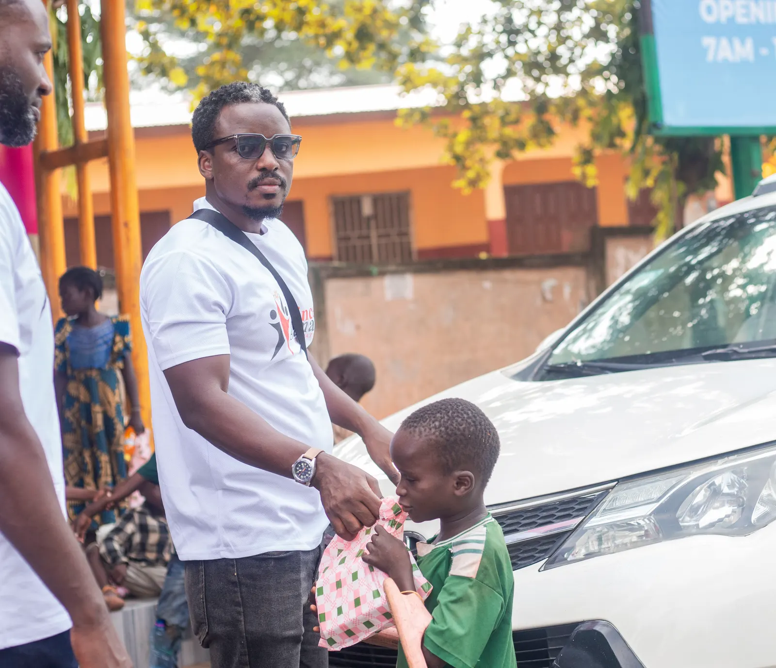 Prince Asamany handing a care package to a boy during a street outreach in Ejisu