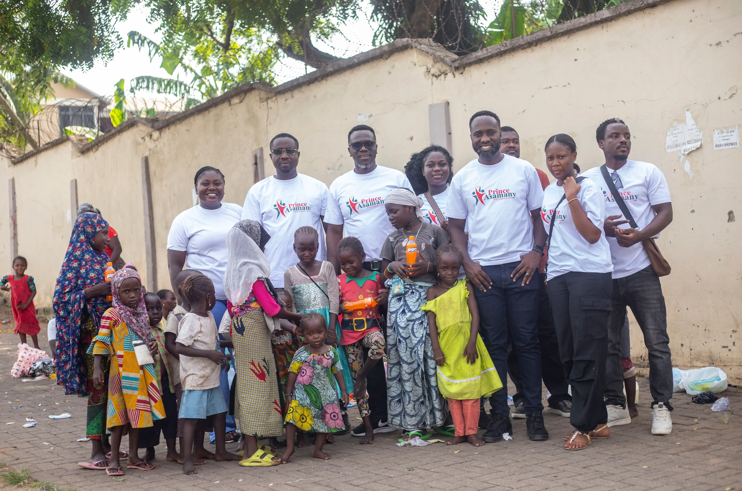 Founder Prince Douglas Asamany standing with foundation volunteers, mothers, and smiling children in Ashanti Region