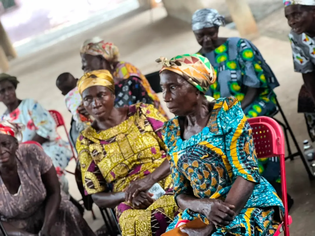 Older community members in colourful traditional dress seated at the gathering