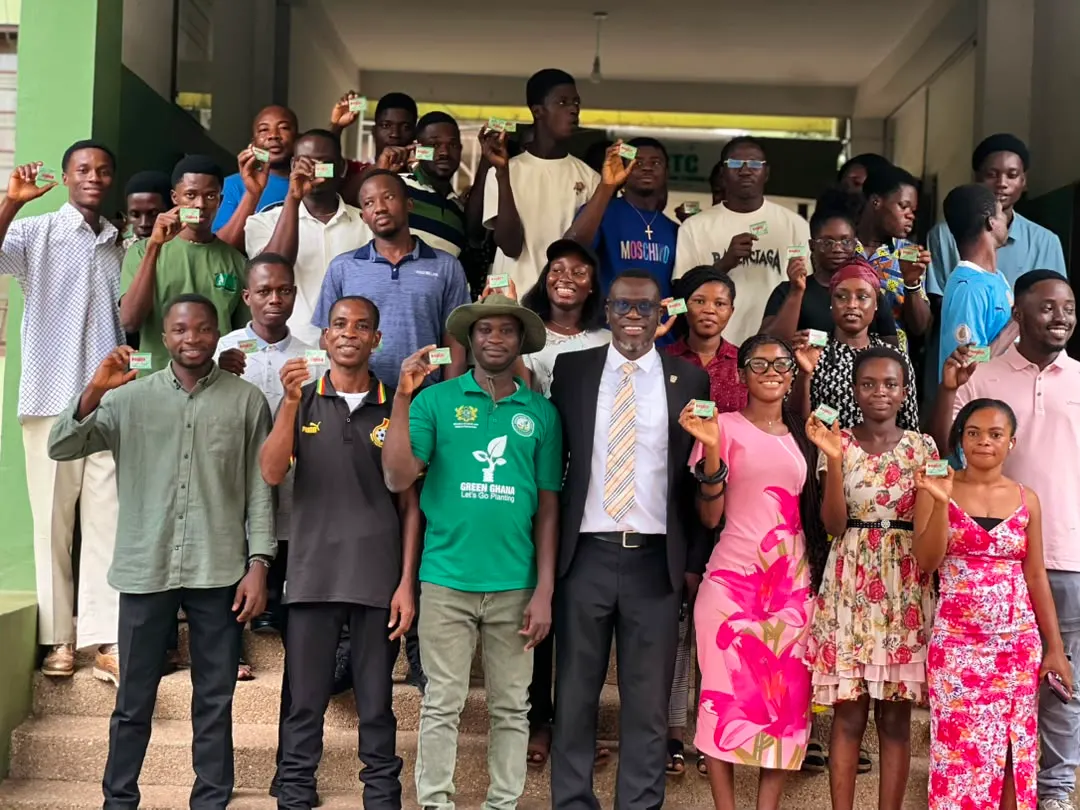 A wider group photo of students on the training-centre steps, several holding up deworming tablets