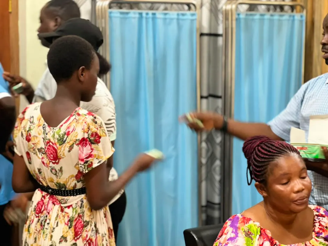 A beneficiary holds her deworming medication as a staff member looks on