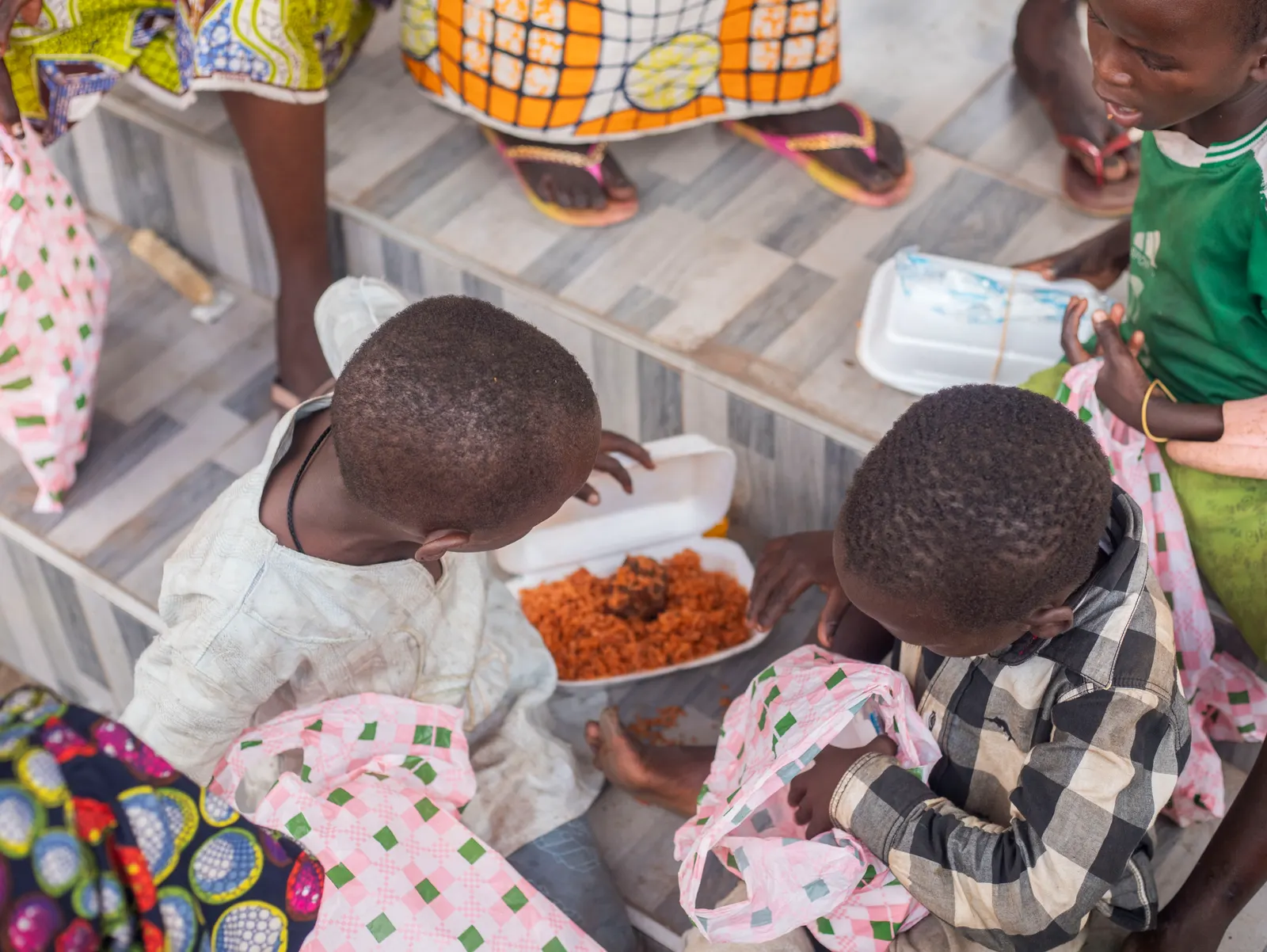 Overhead view of children sharing a meal from food packs distributed during a Joy to the Street relief event